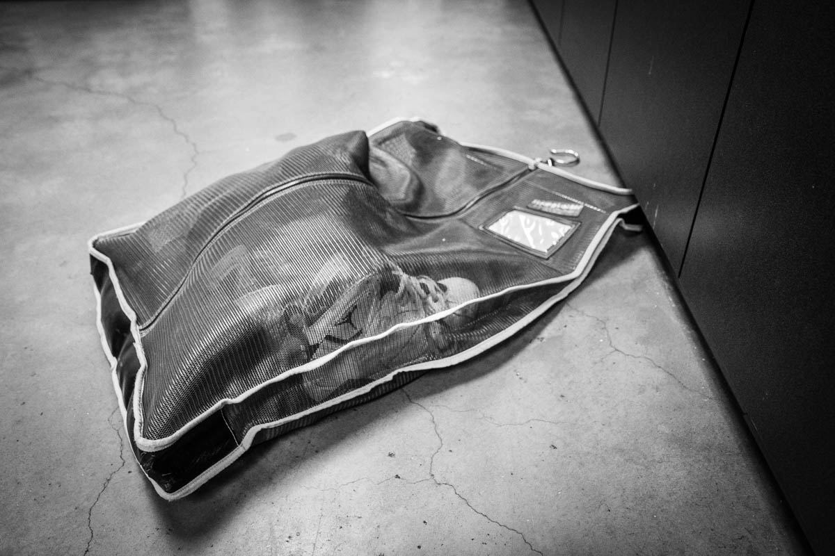 A teen's Air Jordan sneakers and other personal belongings are packed into a bag and loaded onto a giant motorized rack for storage.