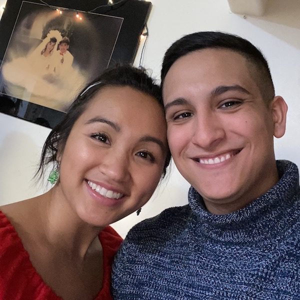 Merk and her boyfriend Samuel smile for a selfie with Merk's parent's wedding picture in the background.